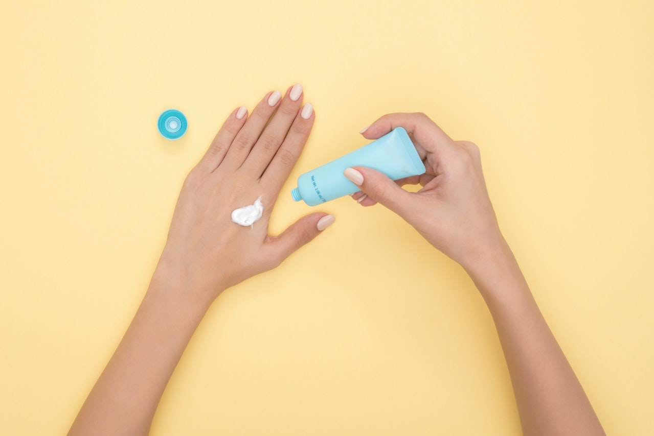 Person Pouring suncreen from a Plastic Tube